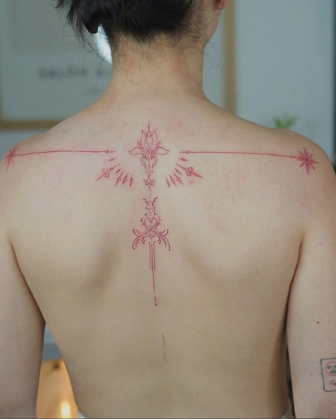 Tatuaj ornamental fineline în roșu, pe omoplați